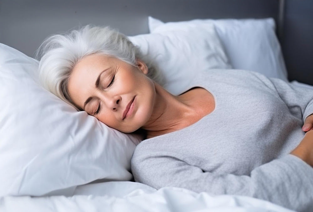 Older woman with gray hair peacefully sleeping on a white pillow in bed, highlighting the importance of healthy sleep for overall well-being.